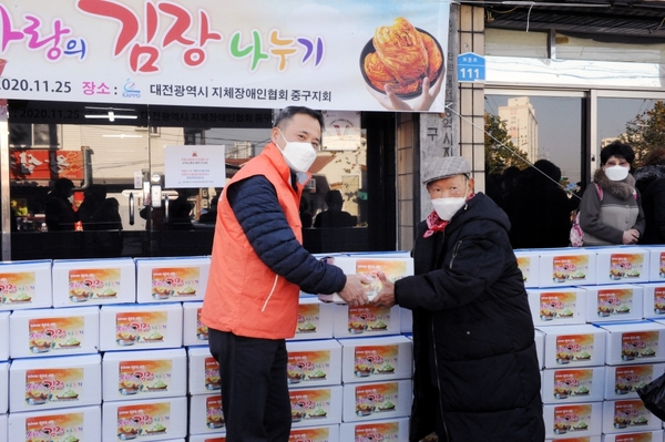 코레일유통 김수환 본부장이 장애인 들에게 김장김치를 나누어 주고 있다.