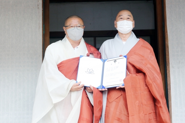 마곡사 주지로 당선된 원경스님(좌측)이 중앙선거관리위원장 세영 스님으로부터 당선증을 교부받고 기념촬영을 하고 있다.
