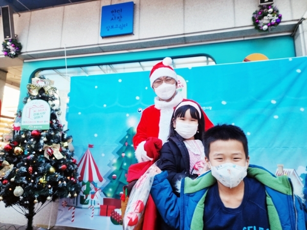 ‘산타’가 대전 한민시장을 기습 방문하여 어린이 고객에게 선물을 나눠주고 함께 촬영하고 있다