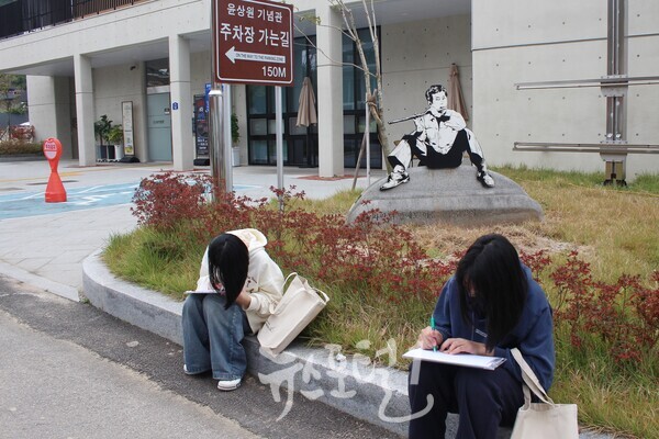 「제1회 윤상원 백일장대회」에 참가한 학생들이 윤상원 기념관 바로 앞에서 글을 짓고 있다.