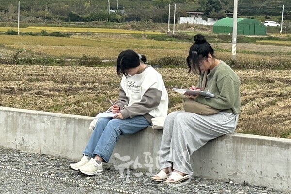 「제1회 윤상원 백일장대회」에 참가한 운남고 학생들이 한적한 가을 들녁을 배경으로 글을 쓰고 있다.